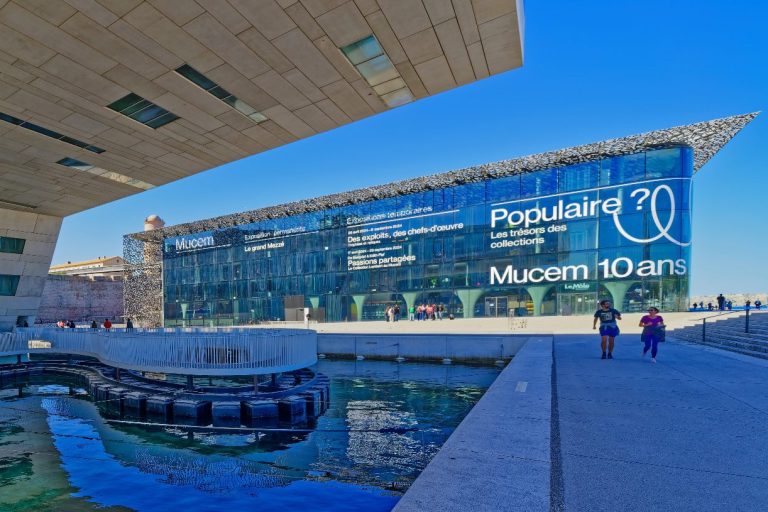 Moderne Architektur des Museums mit Glasfassade und Wasserfläche im Vordergrund.