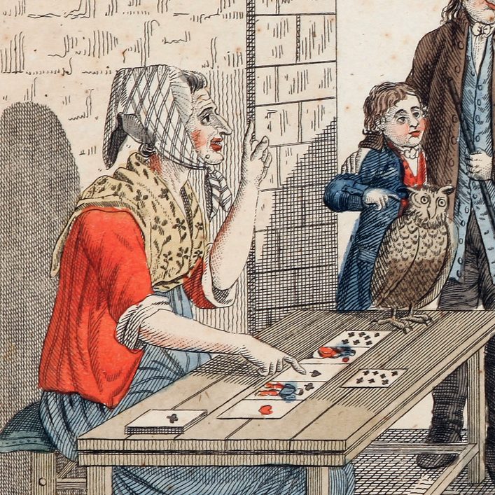 Zwei Personen an einem Tisch, eine Frau mit Kopftuch legt und deutet Spielkarten für eine Person, ein Kind mit Eule schaut zu.